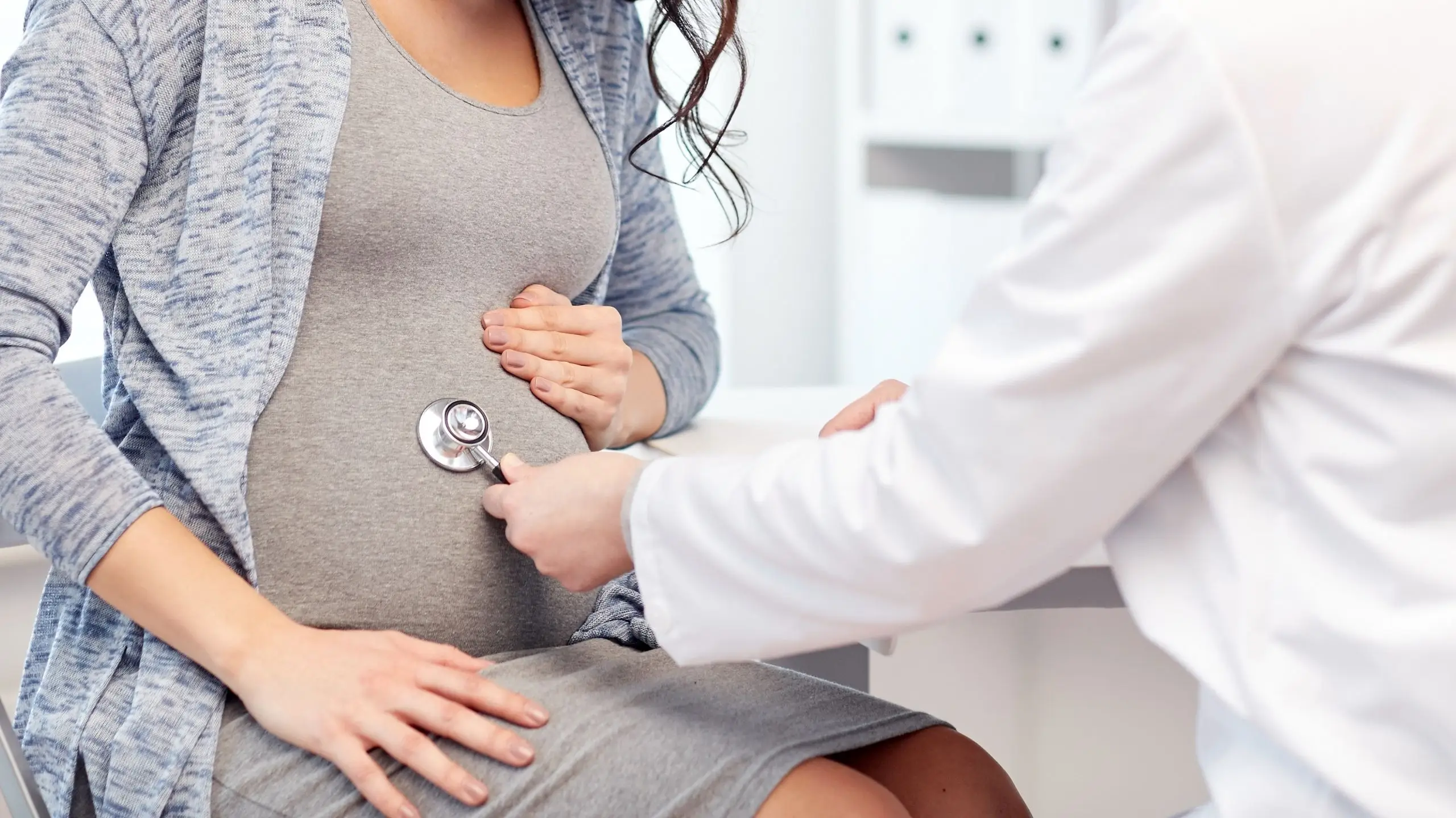 A pregnant woman undergoing a routine prenatal check-up with a female gynecologist using a stethoscope, highlighting specialized care for pregnancy and gynecological health.